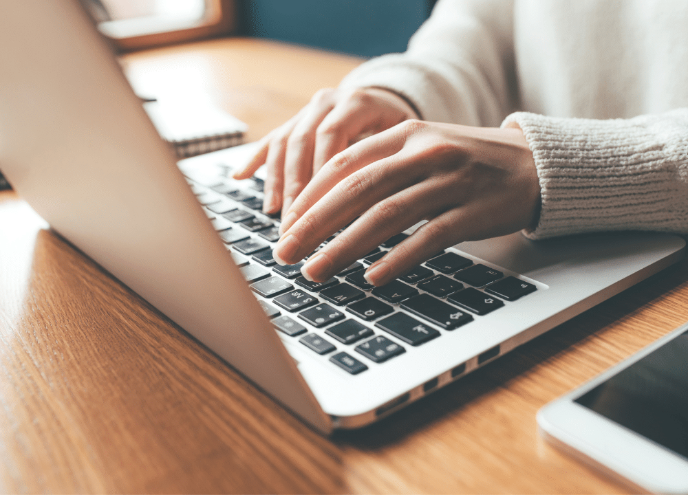 Hands typing on a laptop
