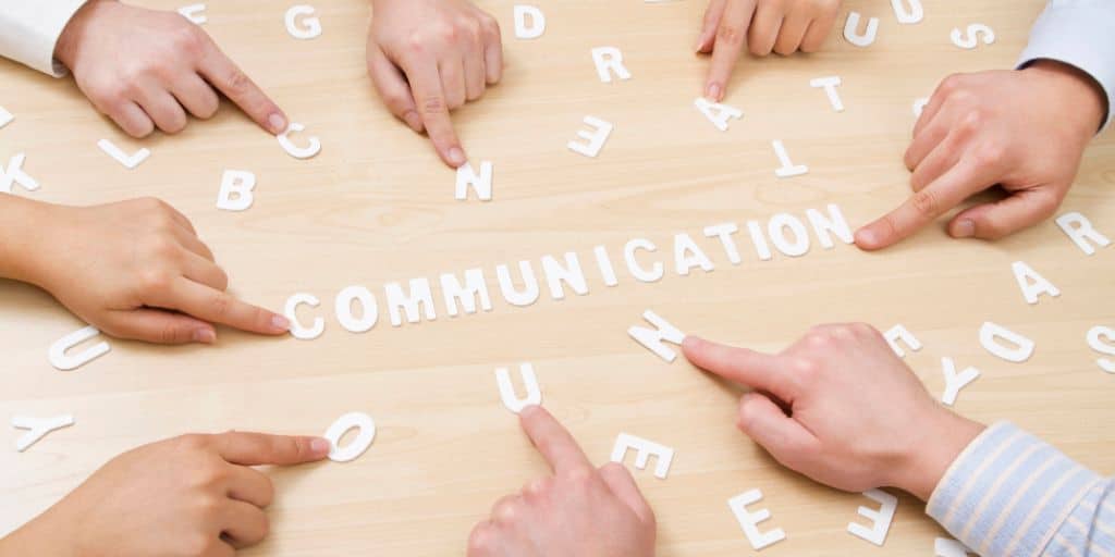 Hands using white letters to spell out "communication"
