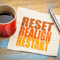 Image of coffee mug with napkin that says reset, realign, restart