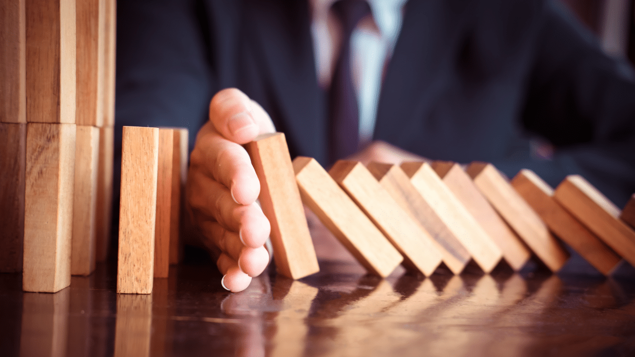Man in suit placing wooden block on a tower concept risk control.