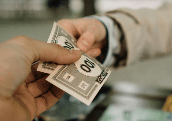 Someone handing monopoly money to another person